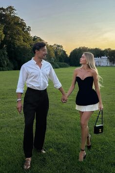 a man and woman holding hands walking across a field