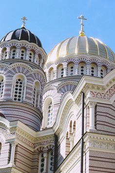 an ornate building with two towers and a cross on it's top, against a blue sky