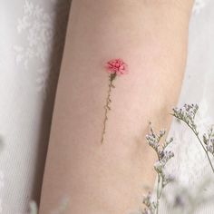 a small pink flower on the side of a woman's leg with tiny flowers around it