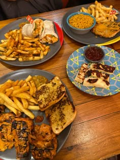 several plates of food on a table with french fries, chicken and coleslaw