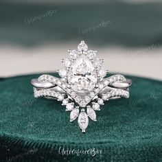 an engagement ring with a pear shaped center surrounded by diamonds