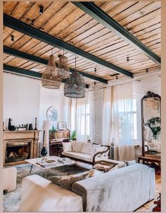 a living room filled with furniture and a fire place under a wooden ceiling mounted chandelier