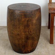 a wooden stool sitting next to a chair on top of a carpeted floor in front of a white wall