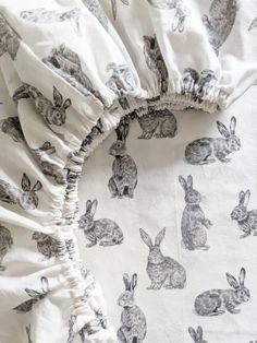 a white bed with black rabbits on it and ruffles at the bottom of the duvet cover