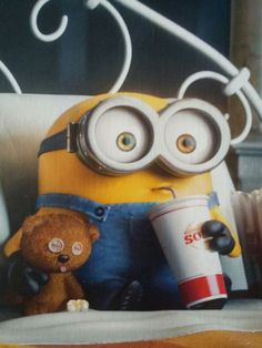 two stuffed animals sitting next to each other in front of a minion holding a cup