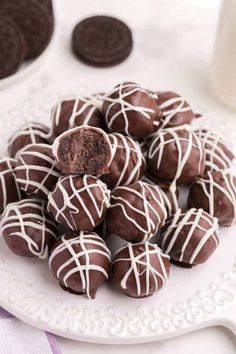 chocolate truffles with white icing on a plate next to milk and cookies