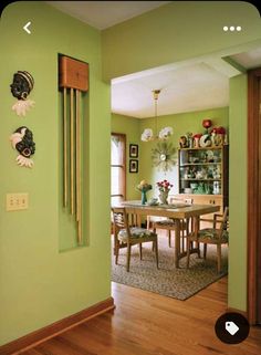 a dining room with green walls and wooden floors