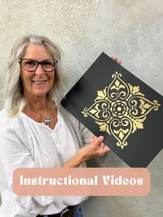 an older woman holding up a black and gold book with the words instructional videos on it