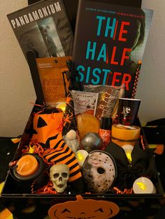 a box filled with books, candles and other halloween related items sitting on top of a table