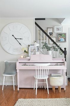 a pink piano sitting in the middle of a living room next to a stair case