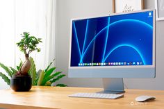 a desktop computer sitting on top of a wooden desk next to a potted plant