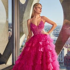 a woman standing in front of a window wearing a pink dress