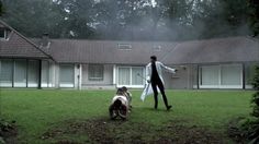 a man standing on top of a lush green field next to a dog