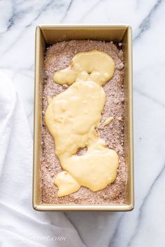 a pan filled with food sitting on top of a white marble counter next to a towel