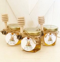 three honey jars with wooden spoons in them and labels on the lids that say honey