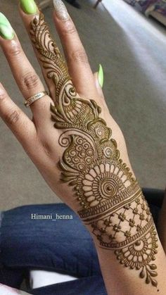 a woman's hand with henna tattoos on her left arm and green fingernails