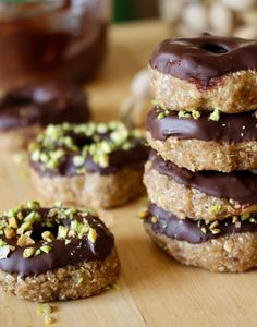 chocolate covered doughnuts sitting on top of a wooden table next to jar of peanut butter