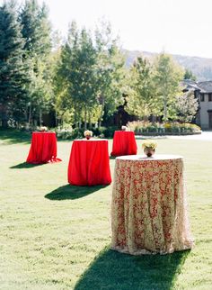 the table is set up with red cloths on it for an outdoor wedding reception