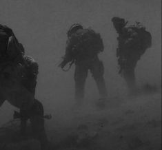 some soldiers are walking through the foggy terrain