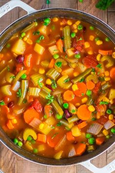 a pot filled with vegetable soup on top of a wooden table