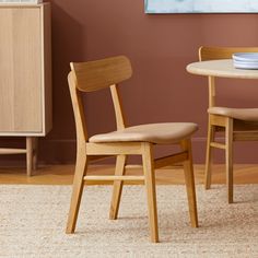 two wooden chairs sitting next to each other in front of a table with plates on it