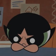 the face of an animated character with big eyes and black hair, wearing a green shirt