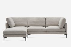 a gray sectional couch with pillows on it's back and arm rests against a white background