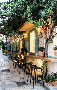 an outdoor cafe with potted plants on the outside