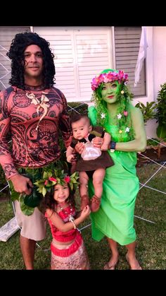 a man and two women are dressed up as hula girls, one is holding a baby