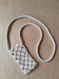 a white crochet purse sitting on top of a piece of paper next to a string