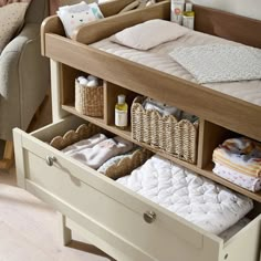 a baby's crib with two drawers and three diapers in the bottom drawer