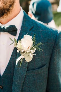 a man in a suit and bow tie with a boutonniere on his lapel