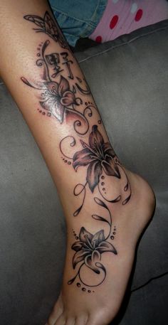 a woman's foot with flowers and vines on the bottom part of her leg