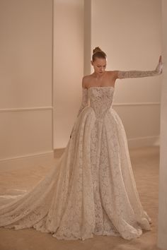 a woman in a wedding dress leaning against a wall with her arms out to the side