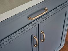 a kitchen with blue cabinets and brass handles