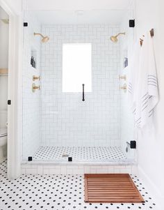 a white bathroom with black and white tile on the floor is featured in this instagram