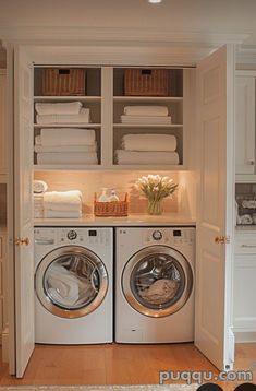 a washer and dryer in a small room with white linens on the shelves