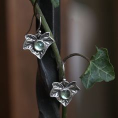 Detailed ivy leaf dangle earrings hand sculpted in fine silver with pale green apatite stones. Unique botanical earrings inspired by the garden. Ivy specifically is a symbolic Yuletide and Solstice botanical. Historically it was made into wreaths and garlands to decorate during the winter. It represents fidelity, faithfulness and healing. These earrings feature detailed ivy leaves that were hand sculpted and molded in silver metal clay before firing. Faceted pale green apatite stones have been set within the leaves. The surface of the silver has been polished to a bright finish with shiny accents. The back of the earrings are textured and reveal hand sculpted bails with Gwydion's Garden signature cherry blossoms. ✥ The drop earrings measure approximately .5" wide x .5" high with a .75" dro Green Tissue Paper, Apatite Necklace, Silver Metal Clay, Green Apatite, Ivy Leaves, Botanical Earrings, Apatite Stone, Wreaths And Garlands, Ivy Leaf