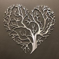 a metal heart shaped tree with branches cut out of it's sides, on a wall