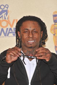 a man with dreadlocks and tattoos on his face is holding scissors in front of his face