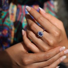 a woman's hand holding an engagement ring with a blue stone in the center