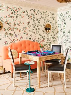 a dining room table with chairs and a couch in front of wallpapered walls