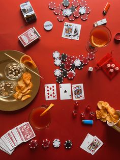 a red table topped with playing cards and drinks