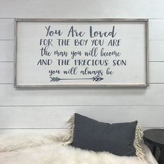 a framed sign on the wall above a bed in a room with white walls and sheepskin rugs