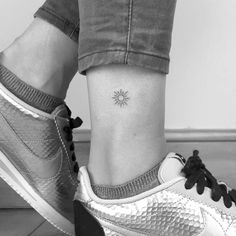 a woman's foot with a small sun tattoo on her left side ribcage