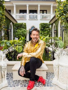 a man sitting on top of a bench in front of a building with columns and plants