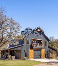 a large gray barn with two story windows on the top floor and an attached balcony