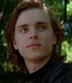 a young man with long hair wearing a black shirt and looking up at the camera