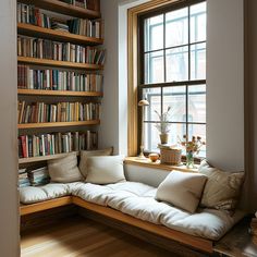 a corner couch in front of a window filled with books