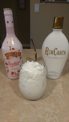 bottles of rum and whipped cream sit on a counter top next to a glass cup